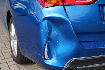Severely dented rear bumper and body panel on a blue car showing collision damage © Aleksandr Fedosov