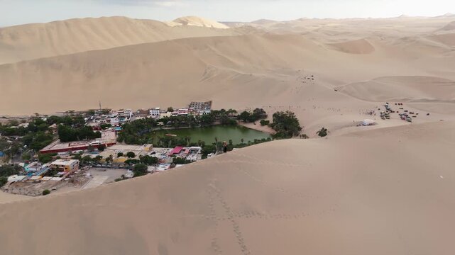 Aerial view of Huacachina oasis in Peru, showcasing sand dunes and a tranquil lake