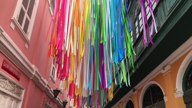 Vibrant colored ribbons and streamers extend across narrow alleyways during local festival in Callao Lima