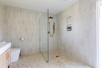 Obraz premium Modern walk-in shower bathroom with glass partition and neutral tile interior