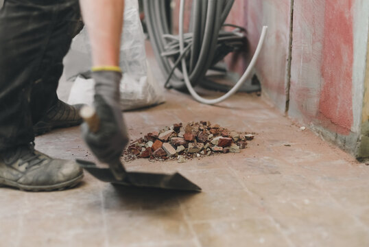 One Caucasian handyman prepares to collect construction stones and debris with a scoop.