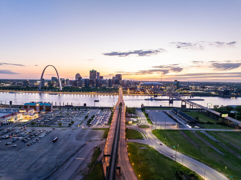 Aerial view of the illuminated st. Louis, missouri skyline at dusk, featuring the iconic Gateway Arch, Mississippi river, and Eads Bridge, creating a breathtaking cityscape
