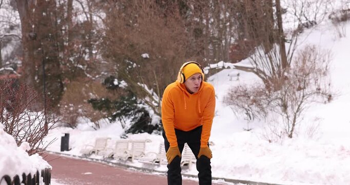 Man with headphones stopping for rest during run in winter park