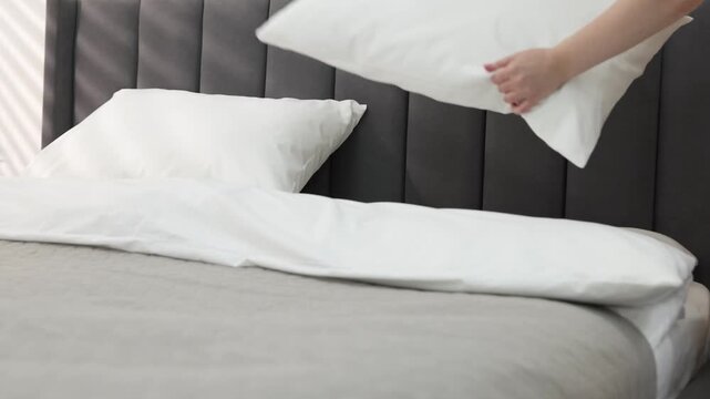 Woman changing bed linens in bedroom, closeup
