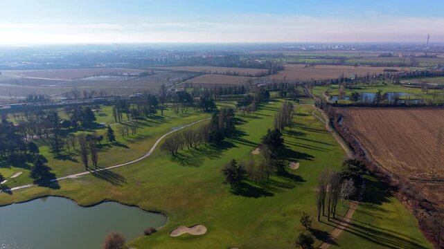 Aerial view of a green golf course with sand bunkers and lake