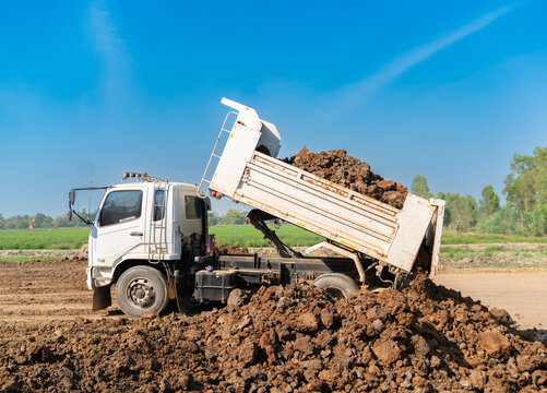 A tipper truck discharging a full load of raw earth and clay at a civil engineering site.