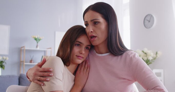 Loving, caring mother embraces teenage girl who needs support after school problem. Caucasian woman tenderly kisses her daughter on forehead and hugs her, offering comfort and support. 4k footage