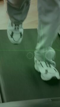 Vertical video: Right foot stepping on treadmill starting feet jogging, hand tapping HUD tracking