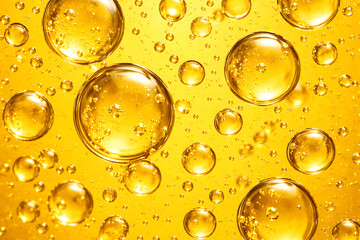 Macro shot of transparent and yellow oil bubbles floating on a bright yellow gradient background. Clean abstract, copy space
