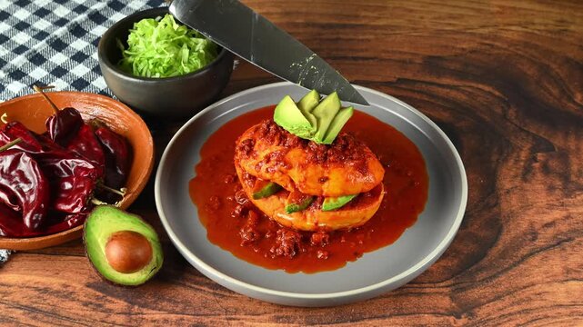 Preparation of a Mexican pambazo, hand placing sliced ​​avocado on a Chancla poblana or drowned sandwich