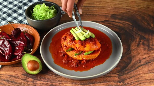 Preparation of a Mexican pambazo, hand placing strips of sliced ​​onion on a Chancla poblana or drowned sandwich