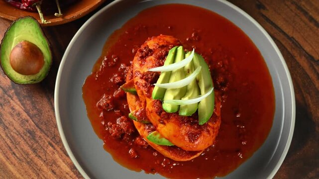 Traditional Mexican food known as chancla poblana with red adobo, chorizo ​​and avocado slices, top view