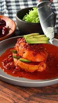 Mexican food, preparation of a Mexican pambazo, hand placing sliced ​​avocado on a Chancla poblana or drowned sandwich