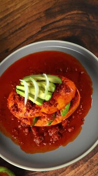 Mexican food, Traditional Mexican drowned sandwich also known as Mexican pambazo or chancla poblana, with red adobo sauce, avocado, and sliced ​​onions, aerial view