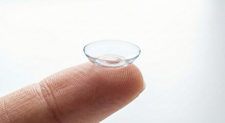 Close-up of a transparent contact lens on a fingertip, vision correction and eye care concept