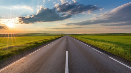 Fototapeta premium Open country highway stretching toward the horizon under a dramatic sunset sky beside vibrant green agricultural fields