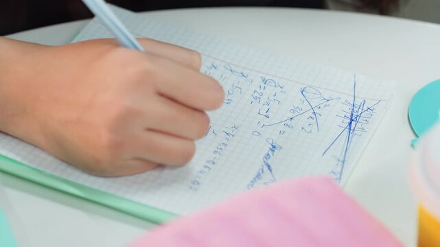 student hand writing notes on graph paper, closeup desk scene with pastel pencil case and cup, focused revision for exam, neat handwriting in blue ink, organized notebook and planner, quiet study