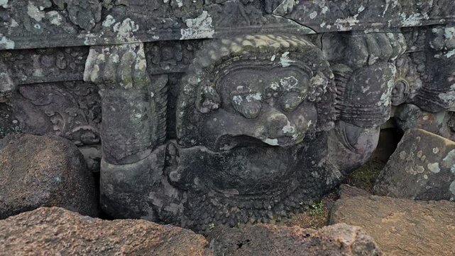 Pan right across weathered stone statues and carvings atop Koh Ker Pyramid Temple, Siem Reap
