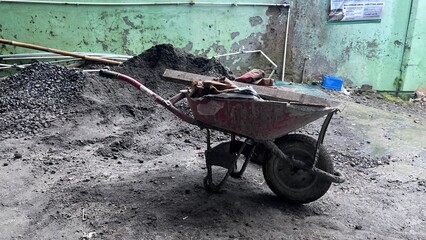 Rusty Wheelbarrow with Pile of Gravel in Industrial Yard