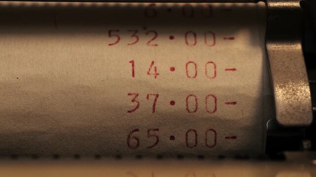 Close up of red printed numbers subtracting with minus symbols on a paper roll in low light