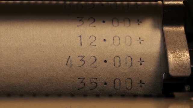 Close up of printed numbers adding up with plus symbols on a paper roll in low light