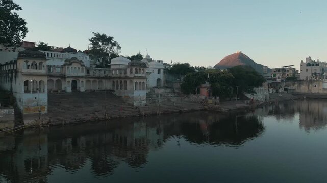 Dolly push-in drone shot of Pushkar Town with the Central Aravalli Mountain Range on the background.