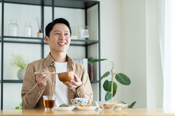 朝食で味噌汁を飲むミドルの男性