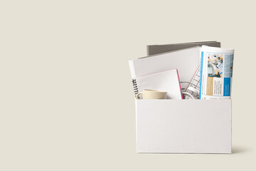 Cardboard moving box with office supplies and cup on white background, closeup