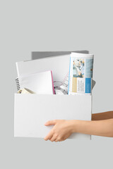 Obraz premium Female hands with office supplies in moving box on white background