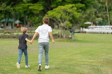 Fototapeta premium Smiling Father and Son Running Together in Park Enjoying Wellness Lifestyle and Healthy Outdoor Activity. Happy Parent and child Jogging Along Lakeside joyful emotional bonding family moment