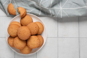 Plate with sweet cookies on white tile background