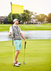 Fototapeta premium Man, flag and play at golf course with smile for recreation, getaway and thinking by lake in summer. Person, golfer and happy with sports gear for game at country club, putter or break on vacation