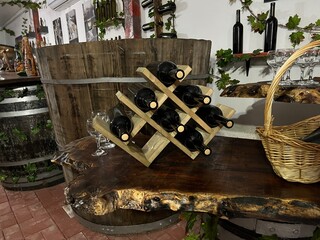Traditional winery tasting area with handcrafted furniture and vintage decor. The scene shows an authentic wine storage room with barrels and shelves in a rural farm style.