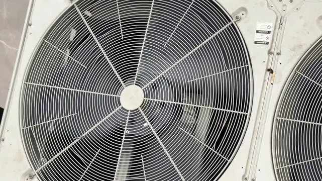 Close-up of industrial fan with metal blades and circular protective grill pattern background