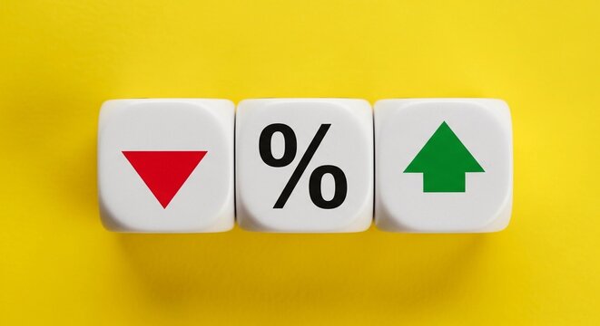 Three white cubes on a yellow background showing a red down arrow, a black percentage symbol, and a green up arrow, representing financial trends and economic indicators.