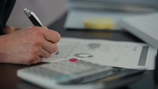 Close-up of business woman accountant making calculations financial data sheet with calculator., Business and financial concept.