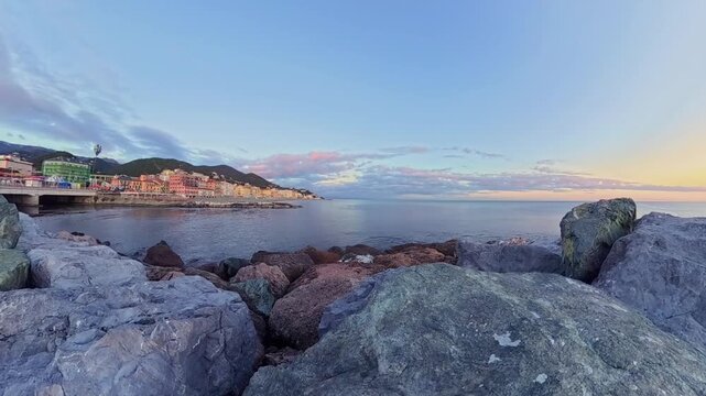 Coastal Scenery Of Varazze Italy Overlooking The Ligurian Sea At Sunset With Rocks In Foreground And Buildings Along The Coastline In The Distance. Timelapse