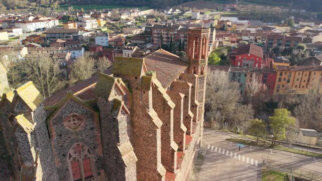 Drone footage orbiting the historic monastery of sant joan les fonts in girona, catalonia, showcasing its romanesque architecture, prominent bell tower, and the surrounding spanish village