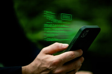 Hands holding a smartphone with glowing green code projected above the device.