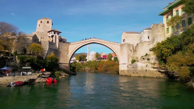 Cinematic drone flight under the historic Stari Most bridge in Mostar, gliding over the turquoise Neretva river, Bosnia and Herzegovina, 4K reveal shot