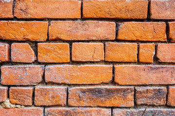Obraz premium Red brick wall with peeling white paint shows weathered texture and aging masonry