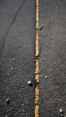 Asphalt road with worn yellow dashed line and cracks