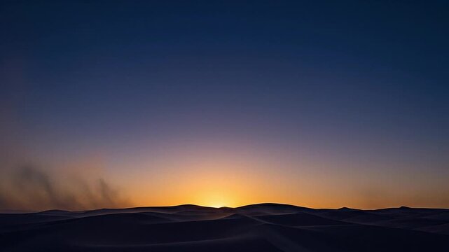 Static shot of the sun rising over desert sand dunes with blowing dust at dawn.