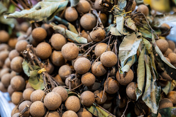 Warm scene with dried leaves and tangled stems. Vivid portrayal of longan fruit bunches amid rustic farm setting evoking sustainability and tradition