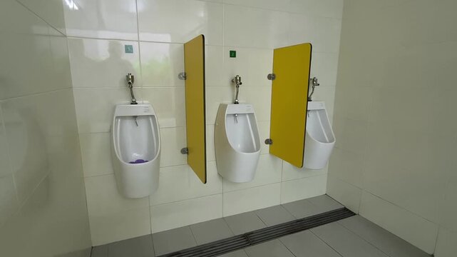 A row of clean ceramic urinals installed in a public men's restroom. Slim privacy walls are placed between each unit to ensure comfort and discretion. The design is modern and functional.