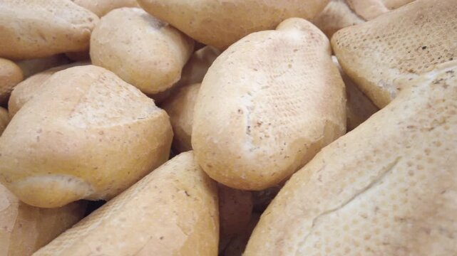 Zoom in shot on fresh bread loaves stacked together, showing crust texture and baking detail.