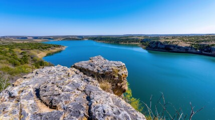 Scenic Overlook of Serene Blue Lake Surrounded by Lush Green Landscape Under Clear Blue Sky