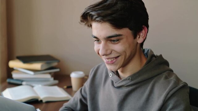 Relaxed student smiling after completing and submitting an assignment at his study desk