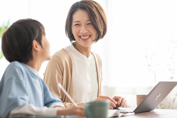 勉強をする男の子と隣で仕事をする母親