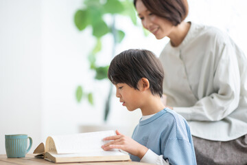 本を読む男の子とソファに座る母親